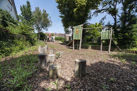 Blick von den Banacierpfosten über die Kletteranlage hin zum Schaukelbereich und den Sitzplätzen am Sandspielplatz